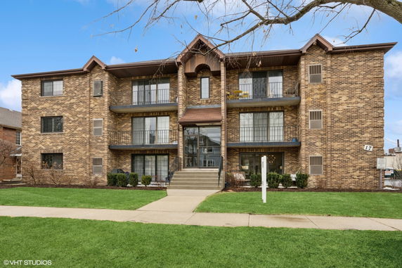 Front view of a multi-story brick apartment building with balconies.