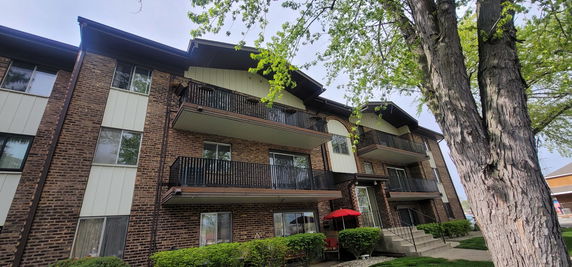 Front view of a multi-story brick apartment building with balconies and large windows.