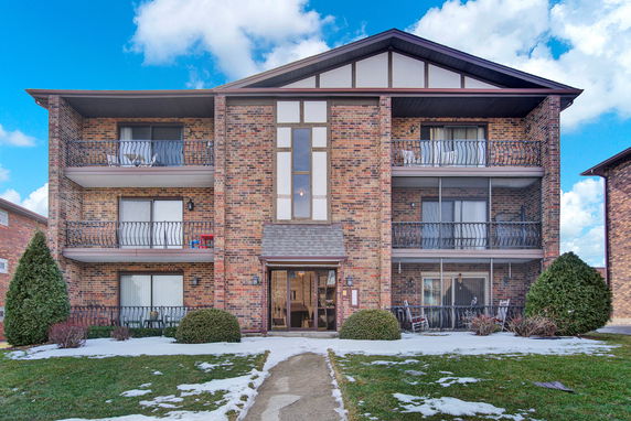 Front view of a three-story brick building with balconies.