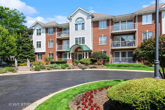 Front view of a multi-story apartment building with balconies and a central entrance.