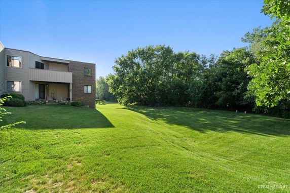 Front view of a two-story building with a brick facade and adjacent grass lawn.