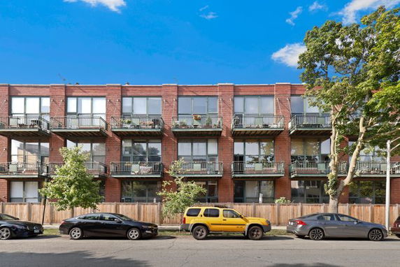 Front view of a three-story brick apartment building with balconies.