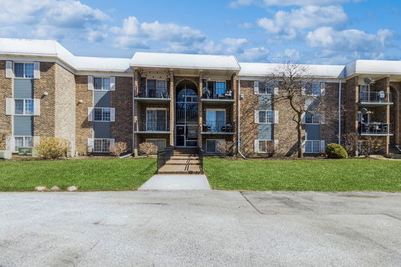 Front view of a multi-story residential building with several balconies and a main entrance.
