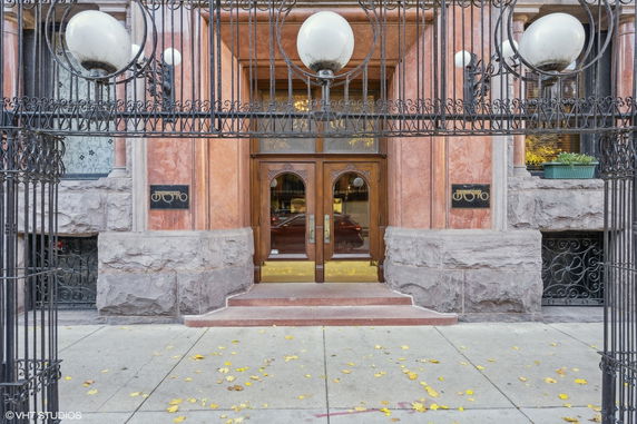 Front view of a building entrance with decorative elements and double wooden doors.