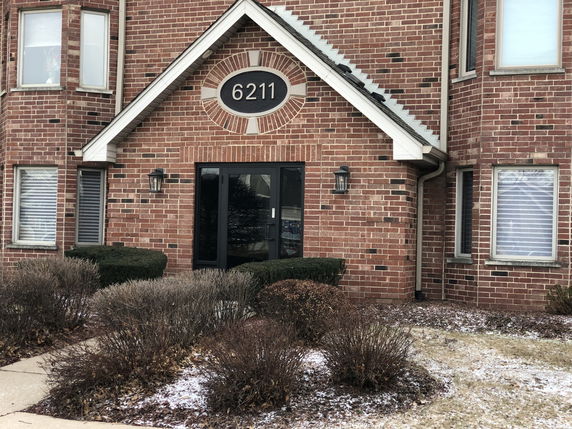 Front view of a brick building with entrance and decorative round window above the door.