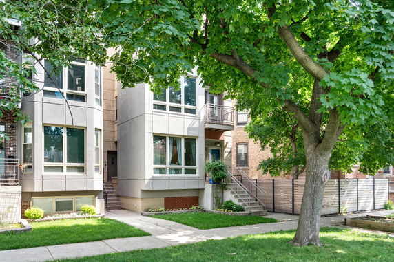 Front view of a contemporary multi-story house with large windows and a small garden area.