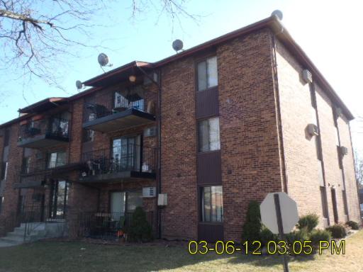 Front view of a multi-story brick apartment building with balconies.