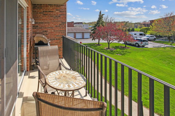 View from a balcony overlooking a parking area and a landscaped lawn.