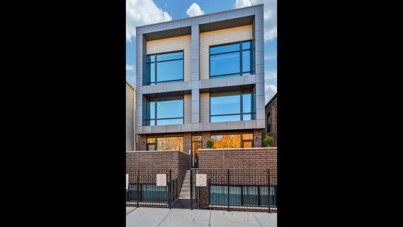 Front view of a modern multi-story building with large windows and a brick exterior.