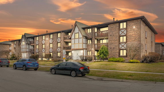 Front view of a multi-story residential building with a brick facade and Tudor-style accents.