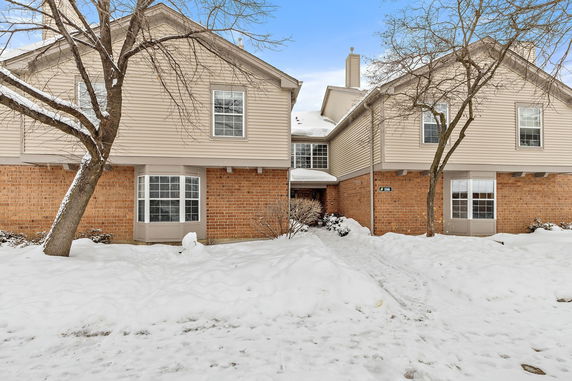 Front view of a two-story house with brick and siding exterior in snowy conditions.