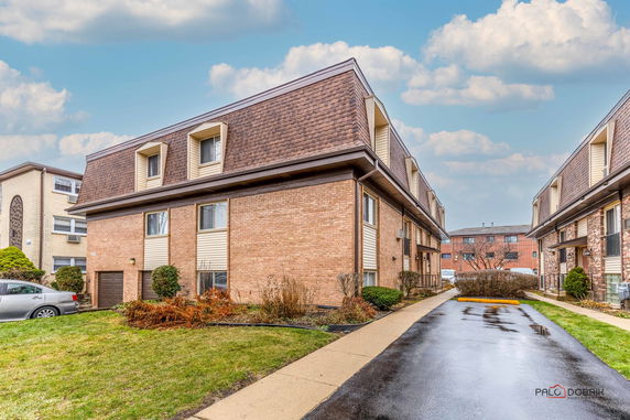 Front view of a multi-story brick apartment building with dormer windows.