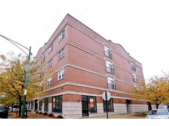 Front view of a four-story brick building on a street corner.