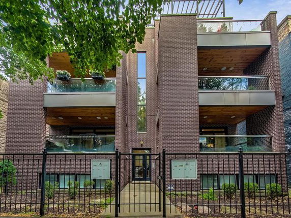 Front view of a modern multi-story building with balconies and brick facade.