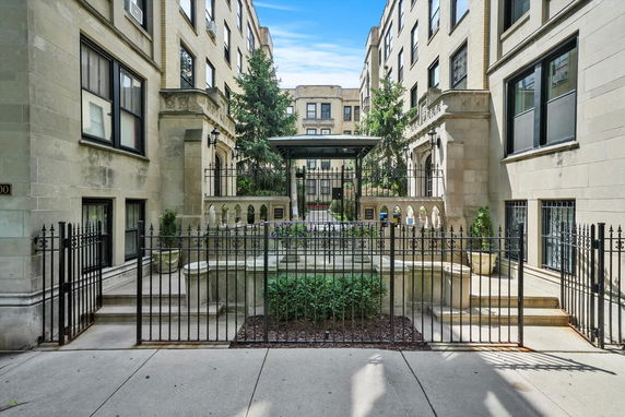 Front view of a multi-story residential building with a gated entrance and courtyard.