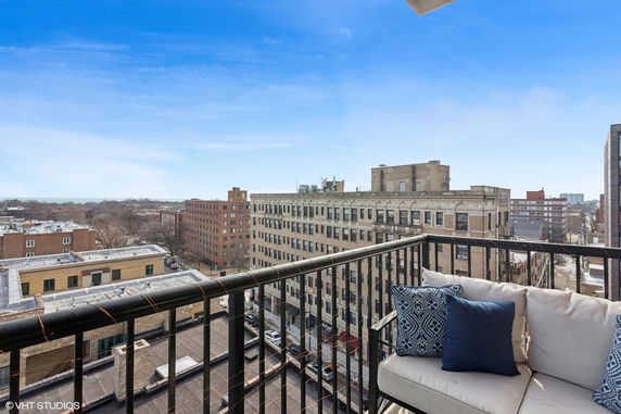 View from a balcony overlooking urban buildings and a distant landscape.