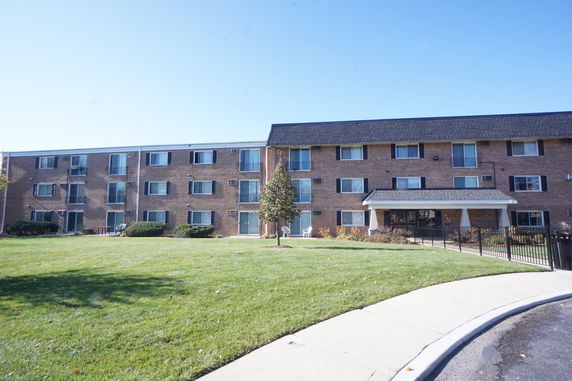 Front view of a three-story brick apartment building with multiple windows.