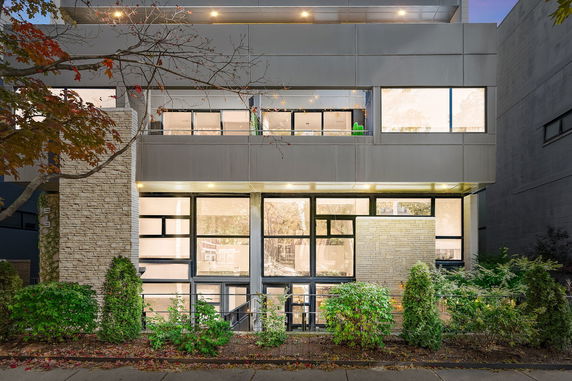 Front view of a modern multi-story building with large windows and brick accents.