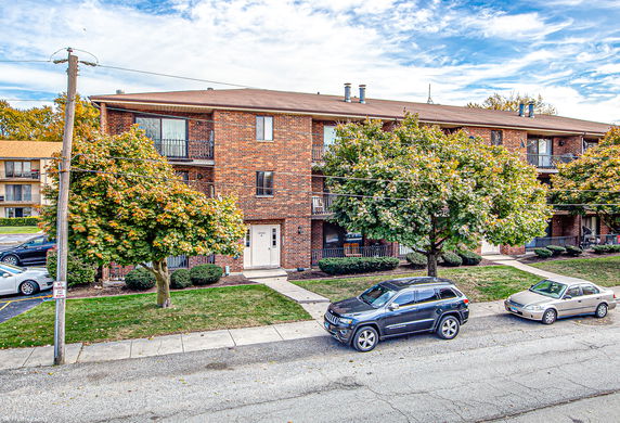 Front view of a multi-story brick apartment building with balconies.