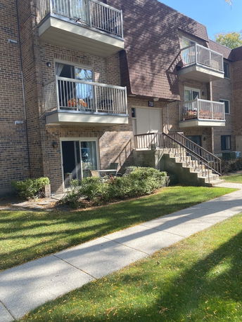 Front view of a multi-story apartment building with balconies and a stairway entrance.