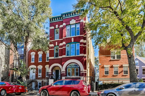 Front view of a multi-story red brick building with arched windows.