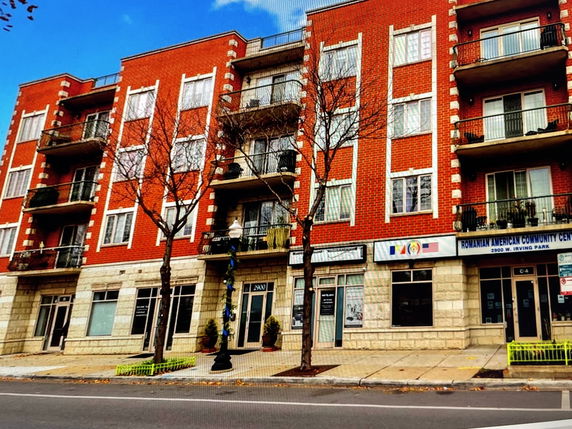 Front view of a multi-story building with red brick facade and balconies.
