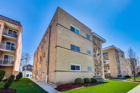 Front view of a multi-story apartment building with brick and stone facade.