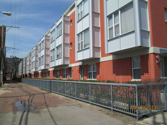 Front view of a row of three-story townhouses with red and white exterior.