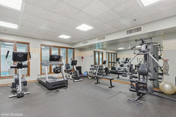 Indoor gym with exercise equipment, including treadmills, weight machines, and free weights.