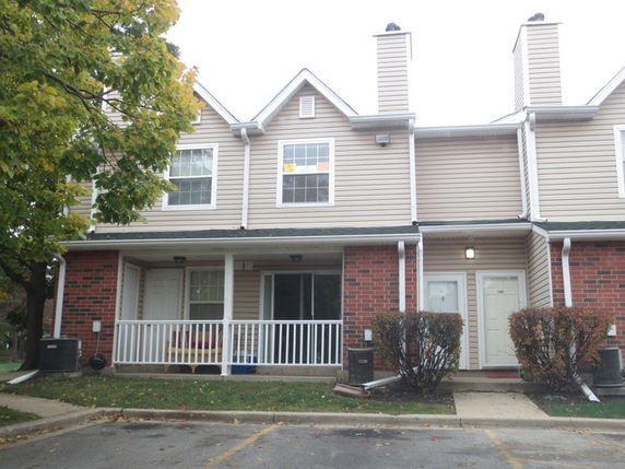 Front view of a two-story townhouse with a small porch and chimney.
