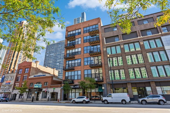 Front view of a multi-story brick building with balconies and storefronts.