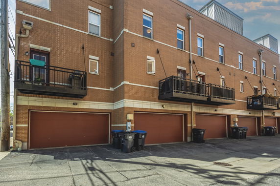 Rear view of a multi-story brick building with balconies and garages.