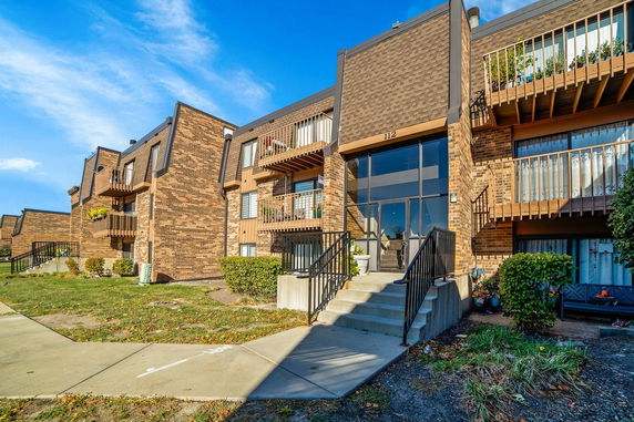 Front view of a multi-story brick building with balconies and a central entrance.