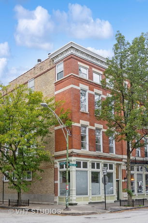 Front view of a multi-story brick building on a street corner.