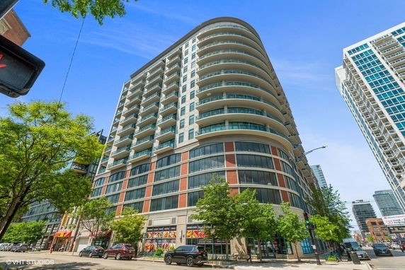 Front view of a multi-story building with curved balconies and commercial shops on the ground floor.