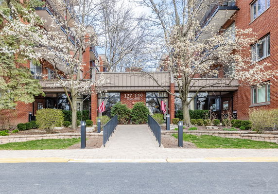 Front view of a multi-story brick building entrance with a path leading up to it.