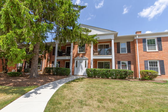 Front view of a brick two-story house with columns and balconies.