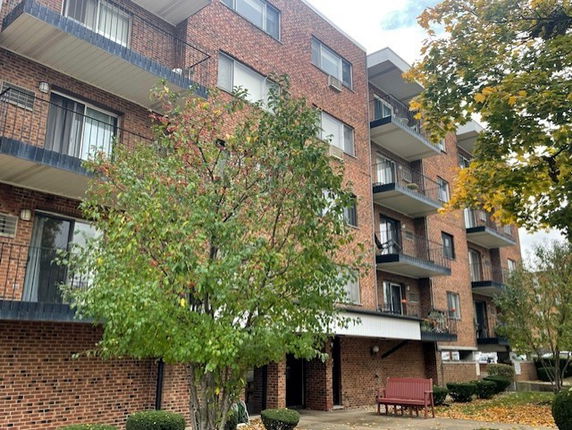 Front view of a multi-story apartment building with brick exterior and balconies.