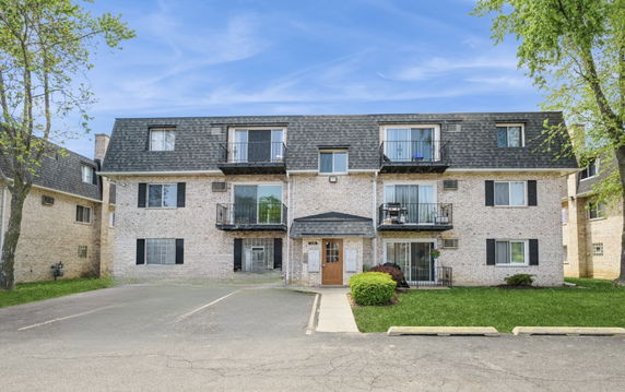 Front view of a three-story brick apartment building with balconies.