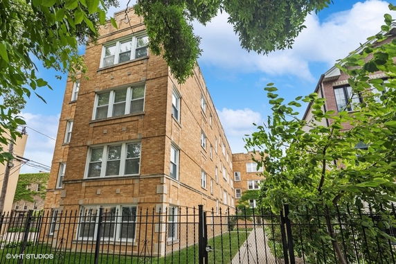 Front view of a multi-story brick apartment building with several windows.