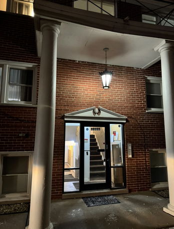 Front view of a brick building entrance with columns and glass doors.