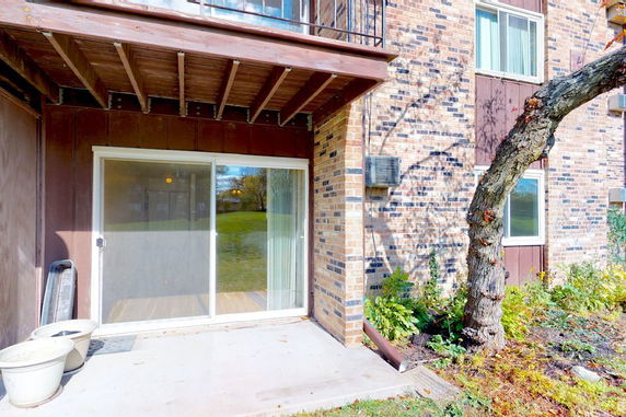 Exterior view of a brick building with a glass sliding door and a small patio area.