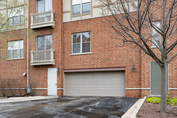 Front view of a brick apartment building with a garage and small balconies.