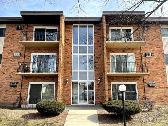 Front view of a multi-story brick building with balconies.