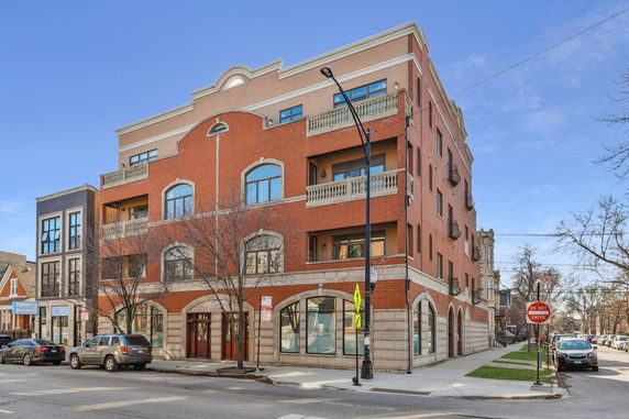 Front view of a multi-story brick building with balconies and large windows.
