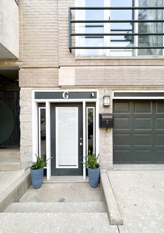 Front view of a house entrance with a modern design and adjacent garage.