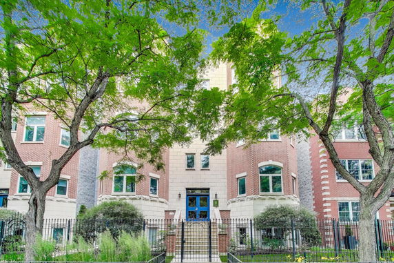 Front view of a multi-story brick apartment building with an entrance staircase.