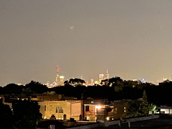 Nighttime panoramic view of a city skyline with illuminated buildings in the distance.
