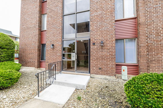 Front view of a brick apartment building with large windows and a glass entrance door.