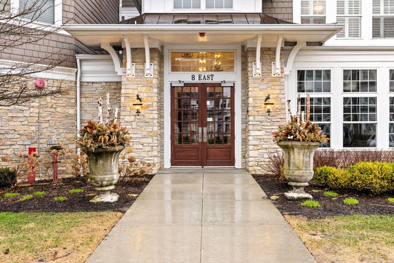 Front view of a building entrance with stone facade and wooden double doors.